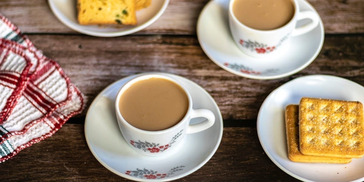 Cană de cafea aburindă lângă un bol de ceai verde matcha pe o masă de bucătărie, dimineața