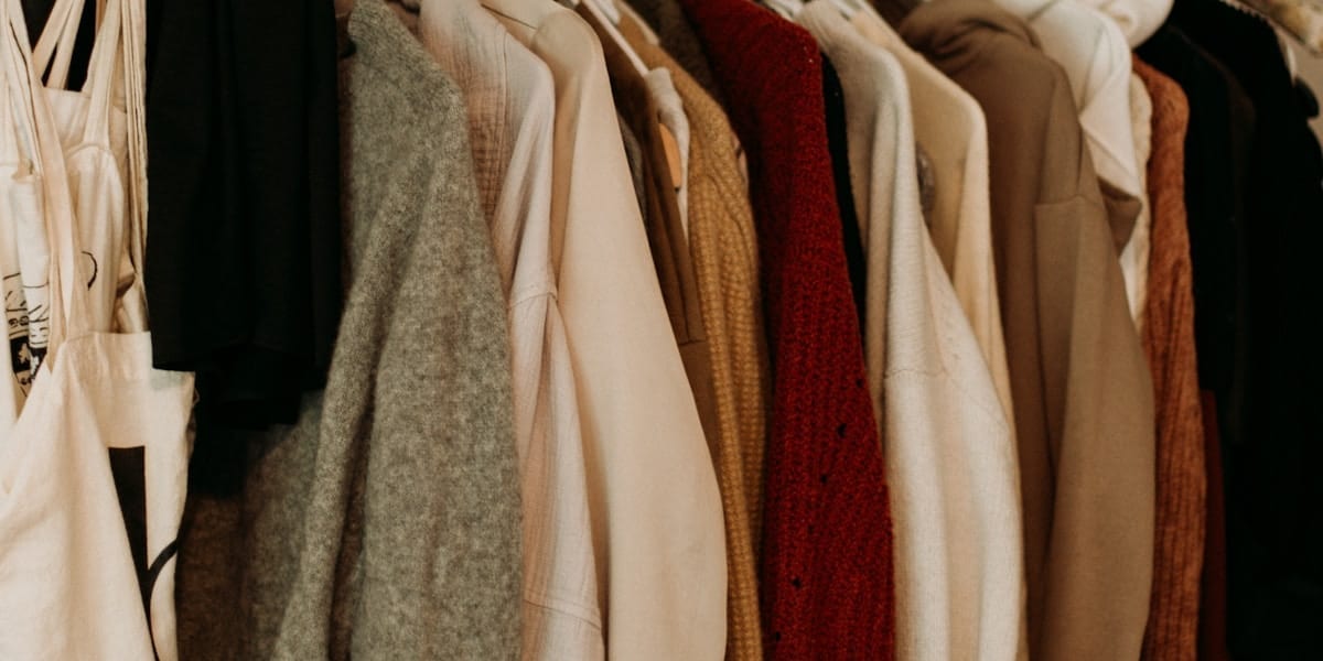 Garderobă organizată cu haine aranjate pe umerașe și pe categorii într-un dressing luminos